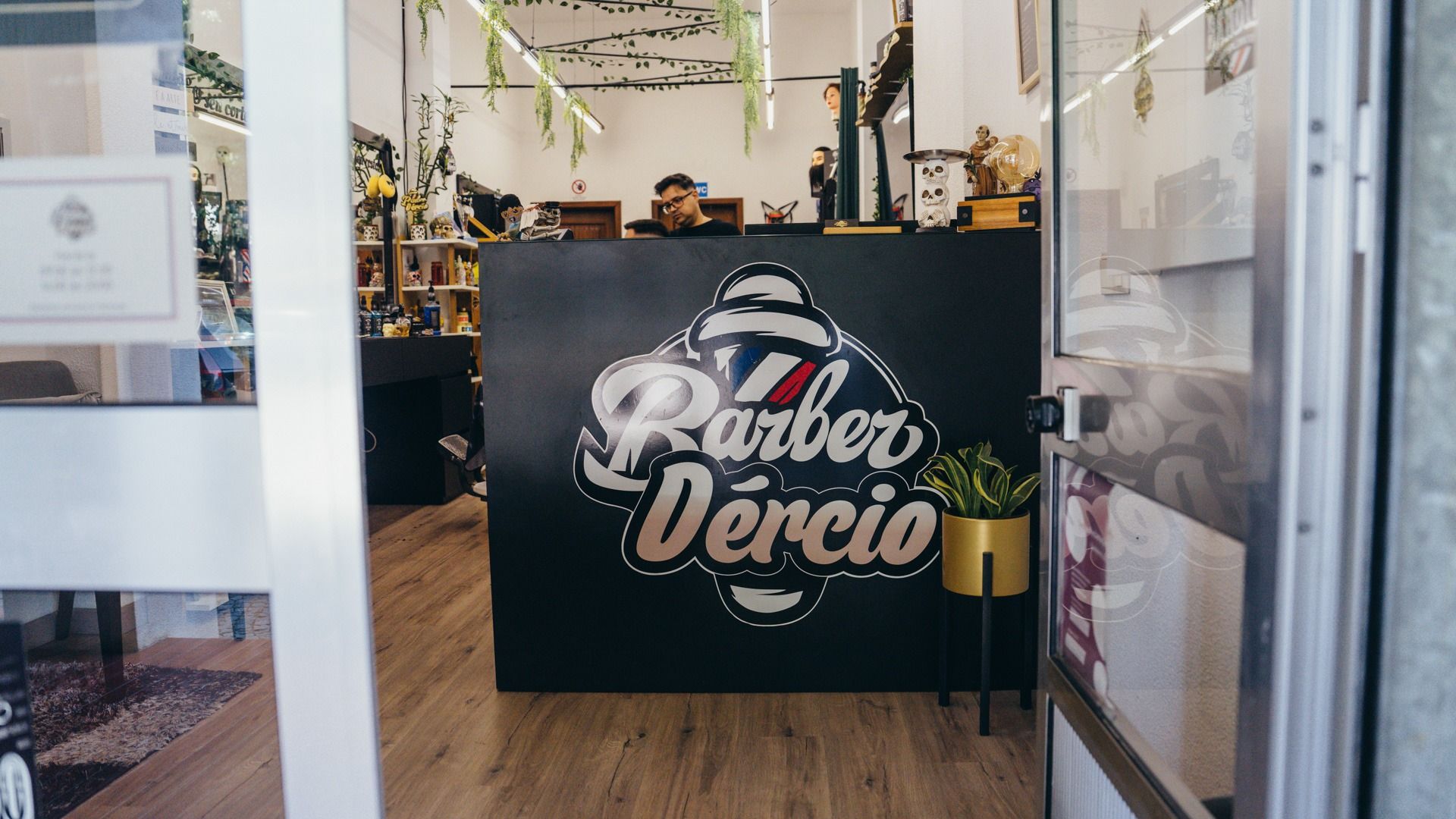 Vista da porta para o balcão preto com o logótipo Barber Dércio.